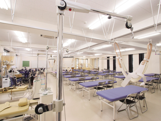 【小倉南区キャンパス】運動療法室／物理療法室。理学療法で使うリハビリ機器を備えた実習室。多人数の講義も可能な広さと学生一人ひとりが使用できる機器数があります。